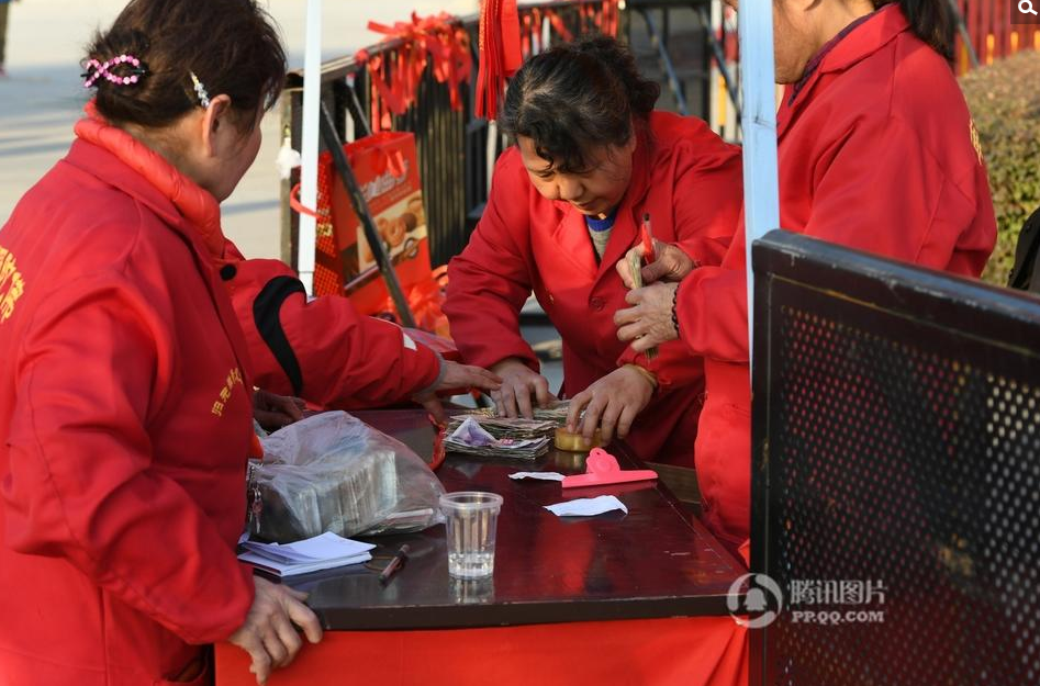 寺庙的工作人员在清理香客扔在庙里的硬币及纸币。