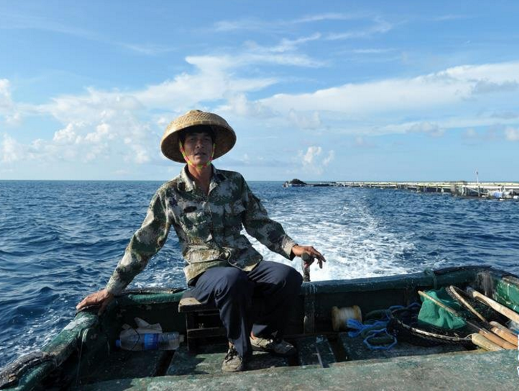 在南沙美济礁礁盘附近,渔民施任平驾驶渔船前往深海养殖基地.