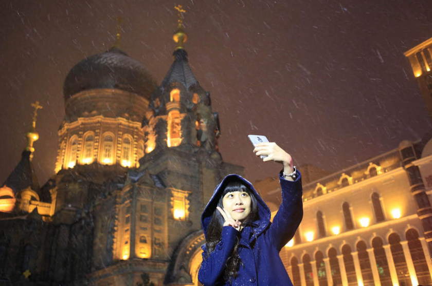 路人在雪中与大教堂留影。