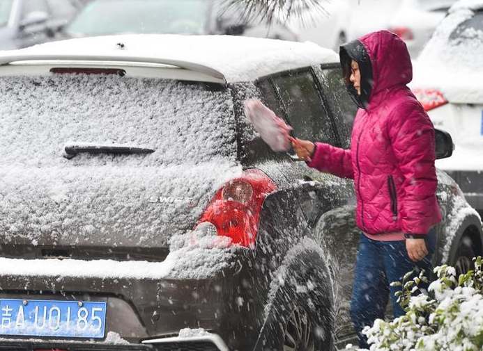 　　一名长春市民在清扫汽车上的积雪。