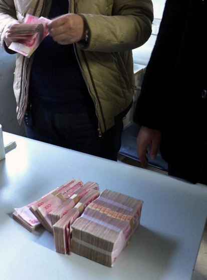 　　拿到工款的农民工正在仔细清点。