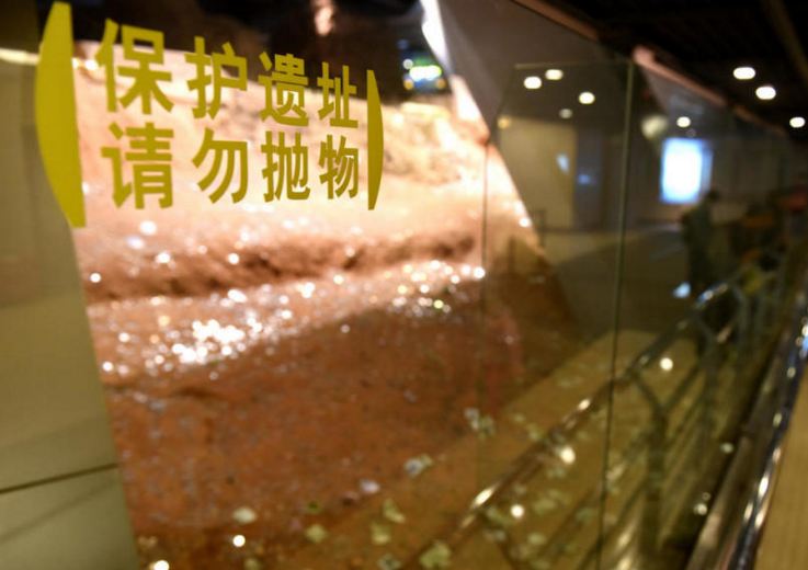 　　而就在游客身边的玻璃墙上，赫然写着“保护遗址，请勿抛物”8个大字。